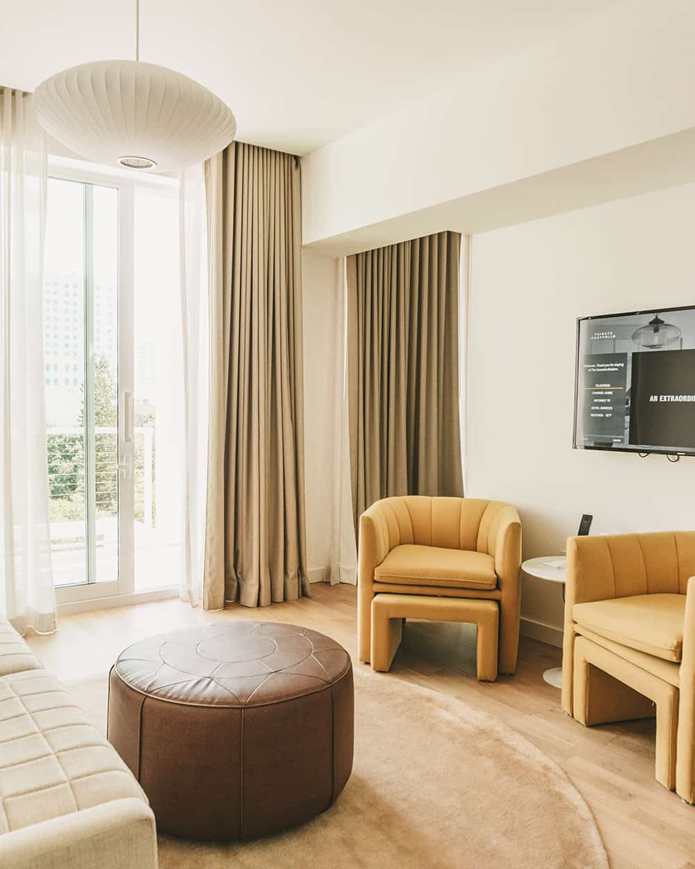 A sunlit hotel suite with lounge seating